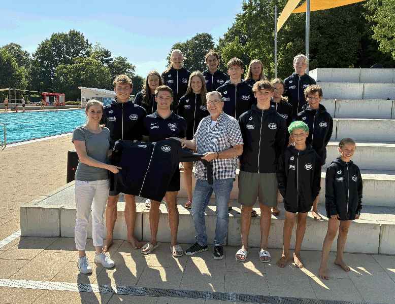 Karin Schäuble und Alexander Bieri von der HUMMEL AG überreichen Schwimmtrainer Thierry Maier die neuen Hoodies für das Schwimm-Team Denzlingen. Bildquelle: Hummel AG